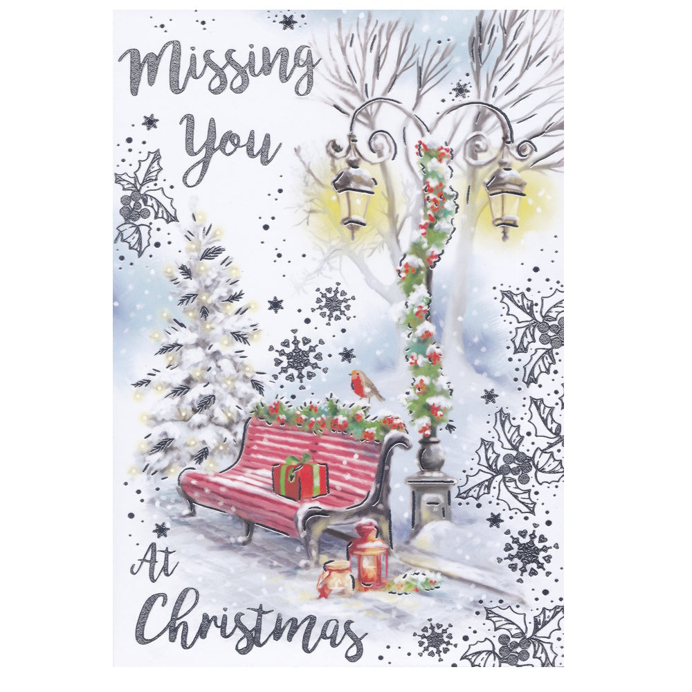 Front of this card features an illustration of a snowy scene with a red bench and lamp post decorated for Christmas, with the text 'Missing You At Christmas'.