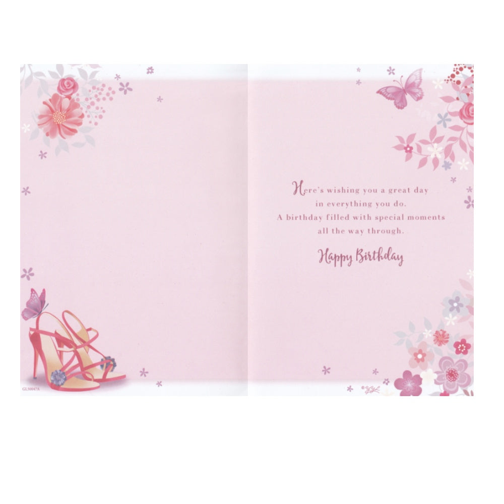 Front of this cousin birthday card features an illustration of a handbag and high heels with a floral background, paired with a message.