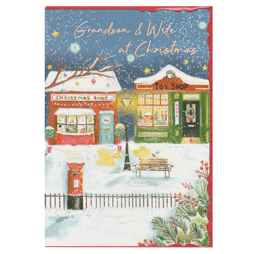 Front of this grandson & wife Christmas card features an illustration of a Christmas themed street with a Christmas shop and toy shop, with the text 'Grandson & Wife at Christmas'.
