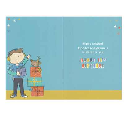 Front of this 11th birthday card features an illustration of boy standing near a stack of presents, paired with a message.