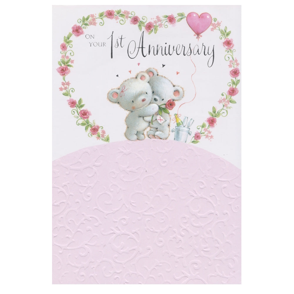 This 1st anniversary card has an illustration of two teddy bears cuddling surrounded by a large flowered heart with the text 'ON YOUR 1st Anniversary'.