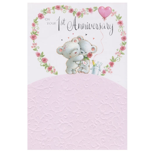 Front of this 1st anniversary card features an illustration of two teddy bears cuddling near surrounded by a large flowered heart, paired with a message.