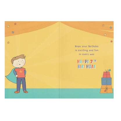 Front of this 7th birthday card features an illustration of a boy dressed in a cape with a stack of presents, paired with a message.