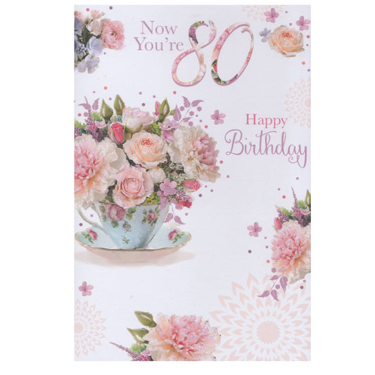Front of this 80th birthday card features an illustration of a flower filled teacup, paired with a message.