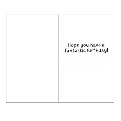 Front of this birthday card features an illustration of pink kitten holding onto a tree branch with a rainbow and balloons, paired with a message.
