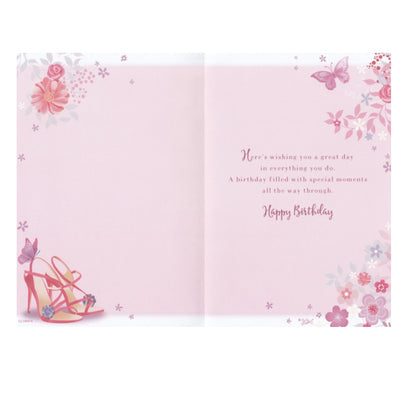 Front of this cousin birthday card features an illustration of a handbag and high heels with a floral background, paired with a message.
