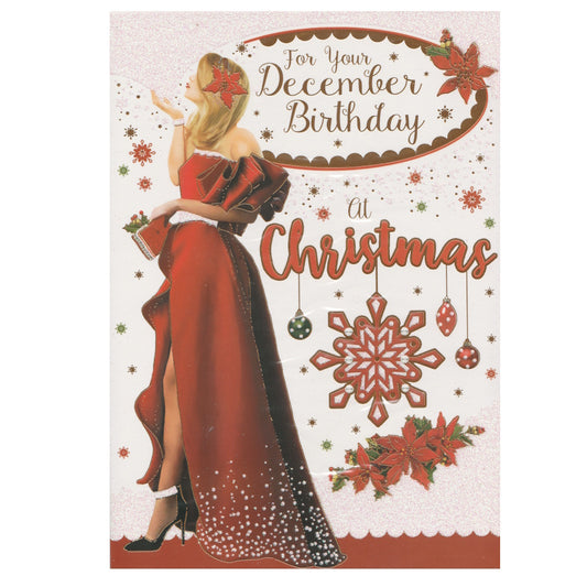 Front of this December birthday card features an illustration of a woman dressed for Christmas in a glittery party dress, surrounded by festive decorations.