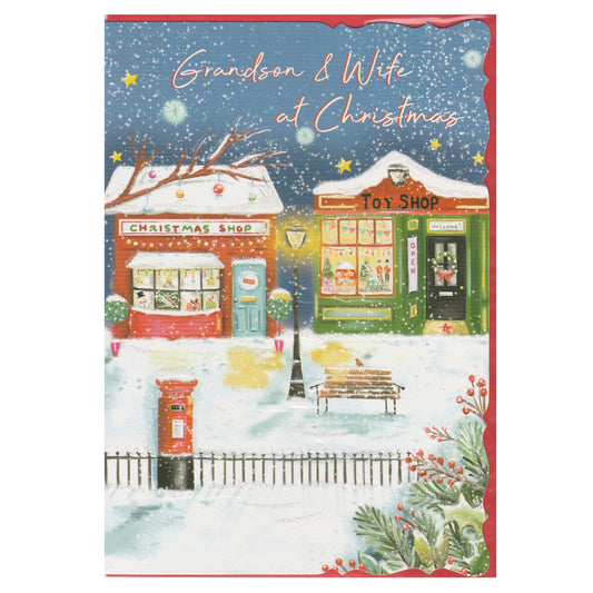 Front of this grandson & wife Christmas card features an illustration of a Christmas themed street with a Christmas shop and toy shop, with the text 'Grandson & Wife at Christmas'.
