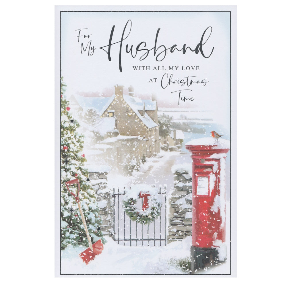 Front of this husband Christmas card features an illustration of a snowy themed street scene with a gate and snow topped post box, paired with a message.