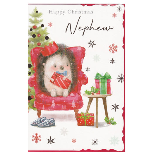 Front of this nephew Christmas card features an illustration of an hedgehog sat in a armchair with a Christmas tree and presents, paired with a message.