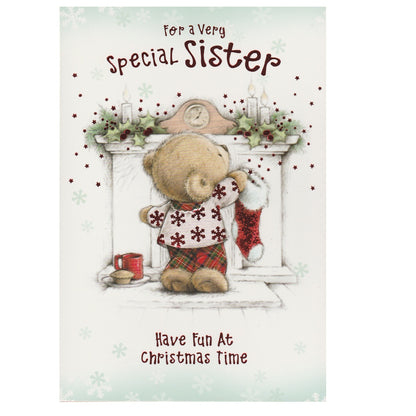 Front of this sister Christmas card features an illustration of a teddy bear hanging up a Christmas stocking on the fireplace, paired with a message.